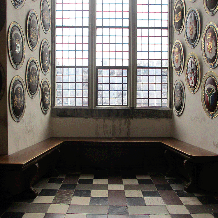 U-shaped bench under a big window with royal from different countries on the wall