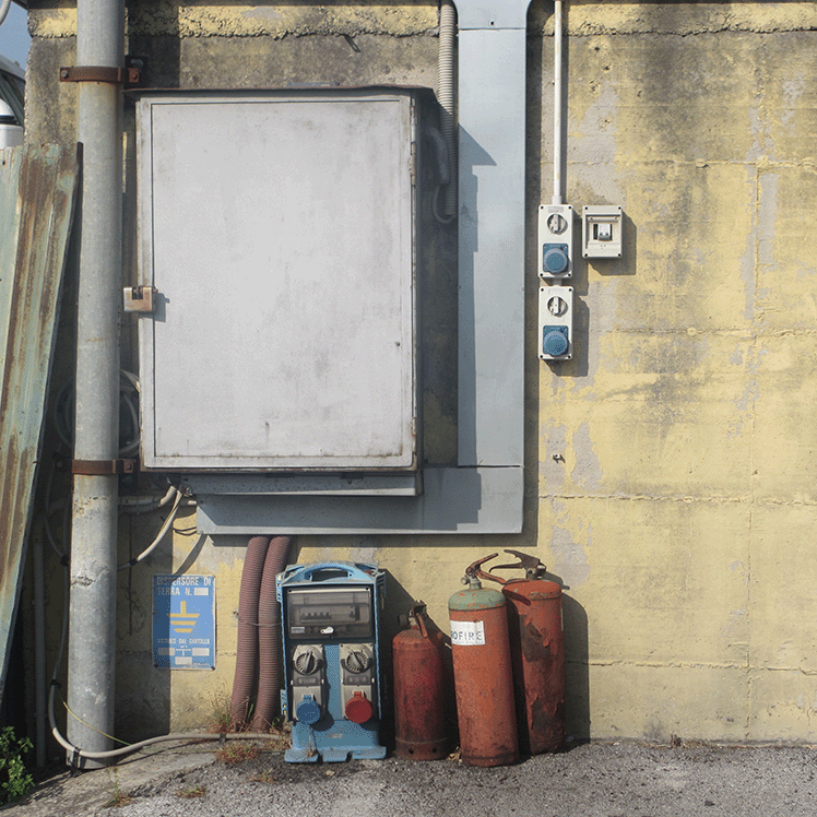 electrical cabinet with rustic pipes and fire extinguishers on a concrete wall outside