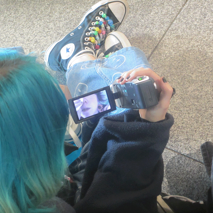 Person with cyan hair from above holding a video camera