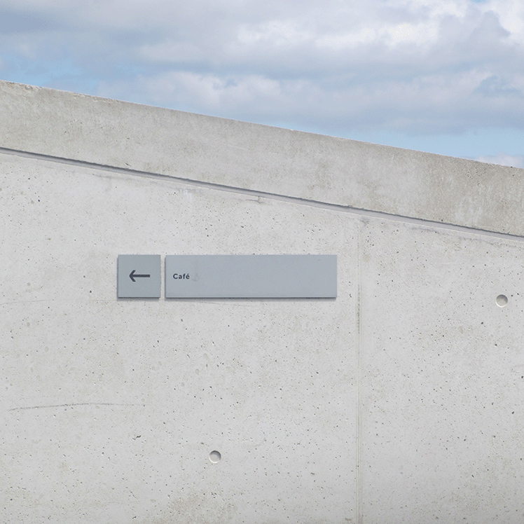 conrete wall with a simple café sign pointing left